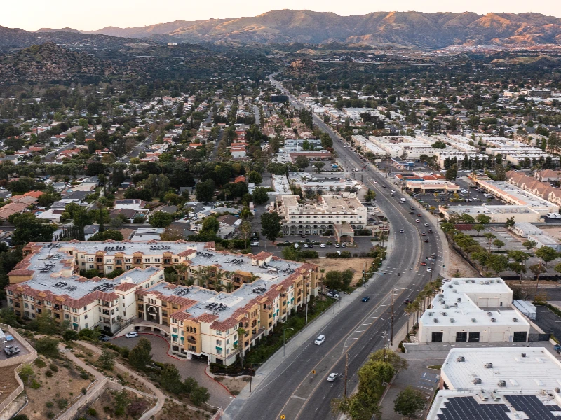 Aerial view of a suburban area with residential buildings, a main road, and mountains in the background. water damage restoration in Chatsworth CA