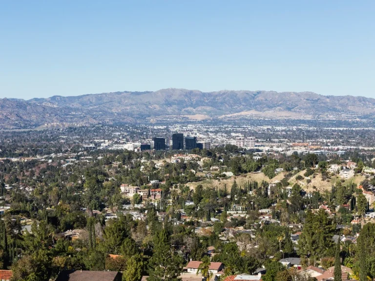 Urban area with scattered buildings and trees in the foreground and mountains in the background under a clear sky. water damage restoration in Woodland Hills CA