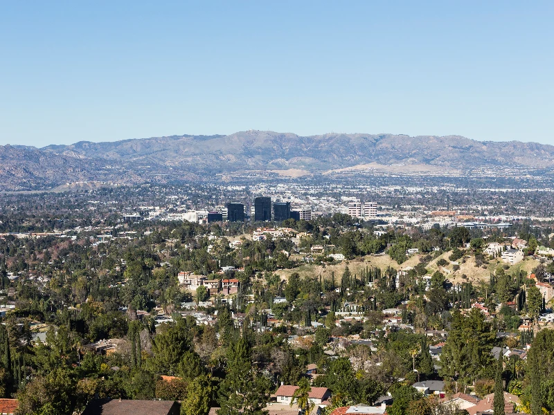 Urban area with scattered buildings and trees in the foreground and mountains in the background under a clear sky. water damage restoration in Woodland Hills CA