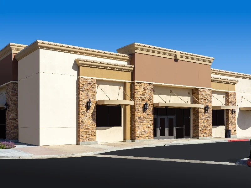 Empty commercial building with stone accents and beige walls under a clear blue sky. commercial restoration services commercial restoration services