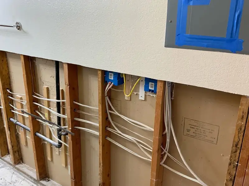 Exposed wall studs with electrical wiring and plumbing pipes in a partially demolished room. water damage restoration
